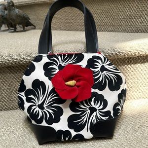 Black & white floral bag with single red flower on front.